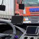 The dashboard of a lorry with two distracting mobile devices hanging in the windscreen